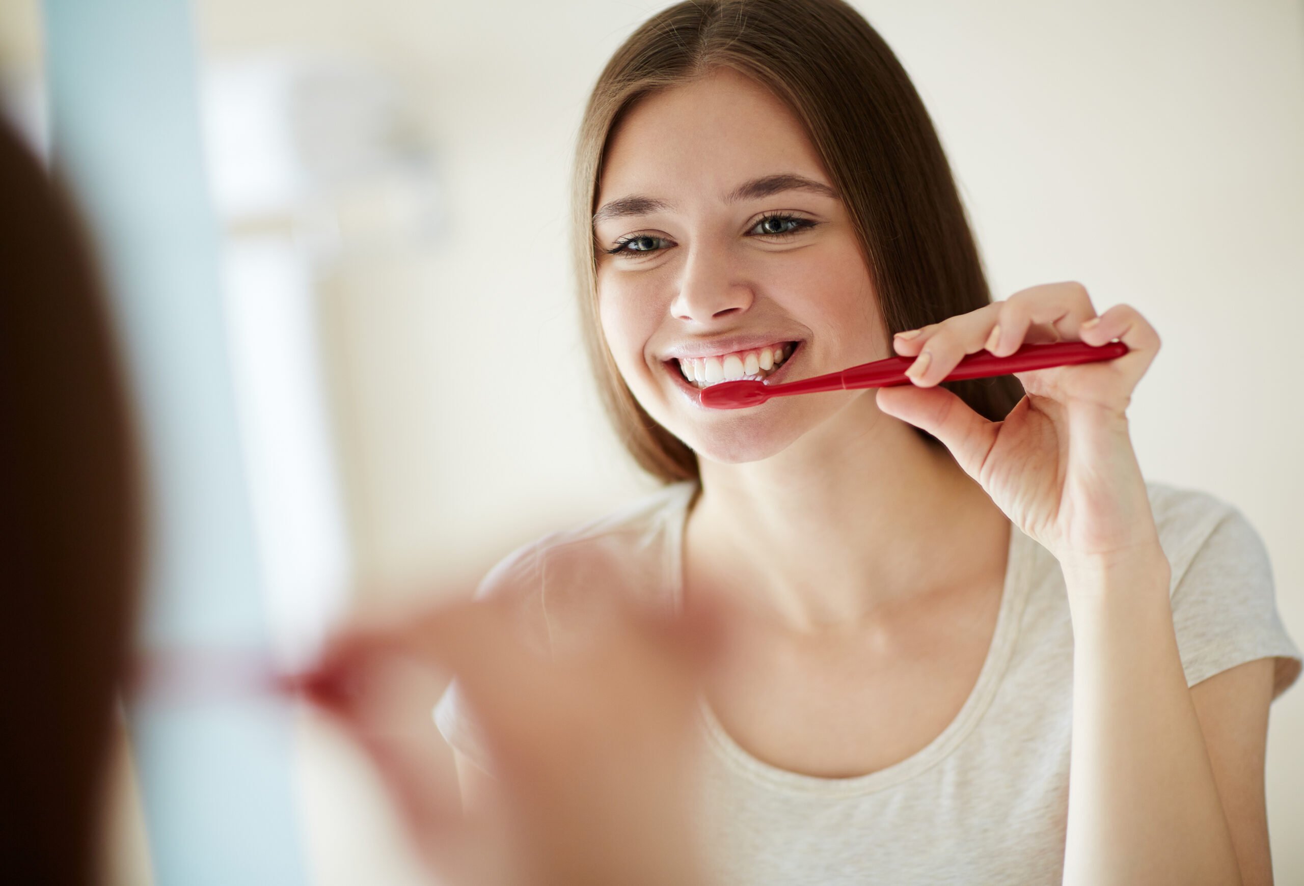 Smiling young woman brushing her teeth