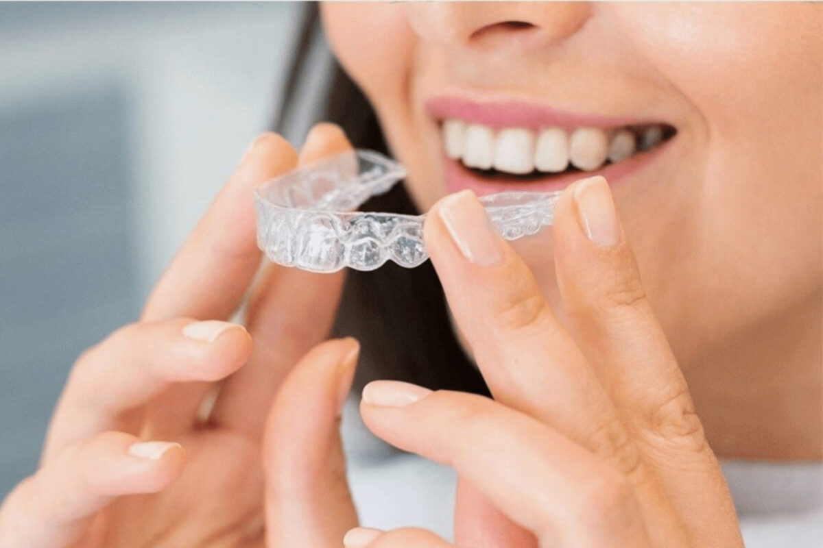 Woman holding clear dental aligners in front of her face